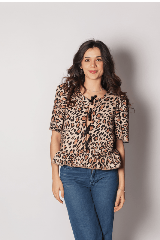 Gros plan sur les nœuds de fermeture noirs et l'imprimé animalier premium de la blouse Léo, création artisanale.