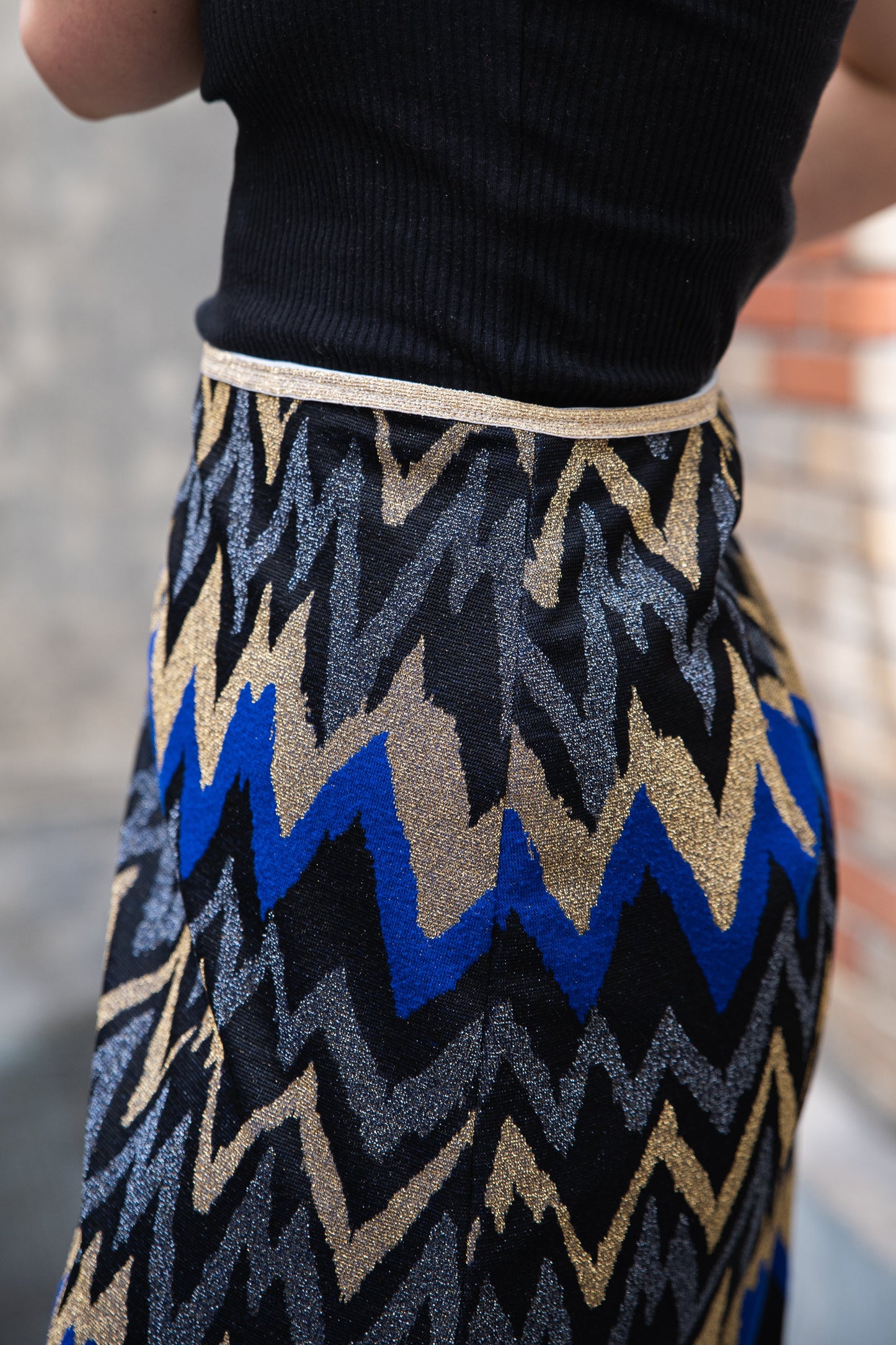 Tenue Parisian Chic : jupe trapèze lurex à motif chevron avec un top fluide noir pour un look de soirée élégant.