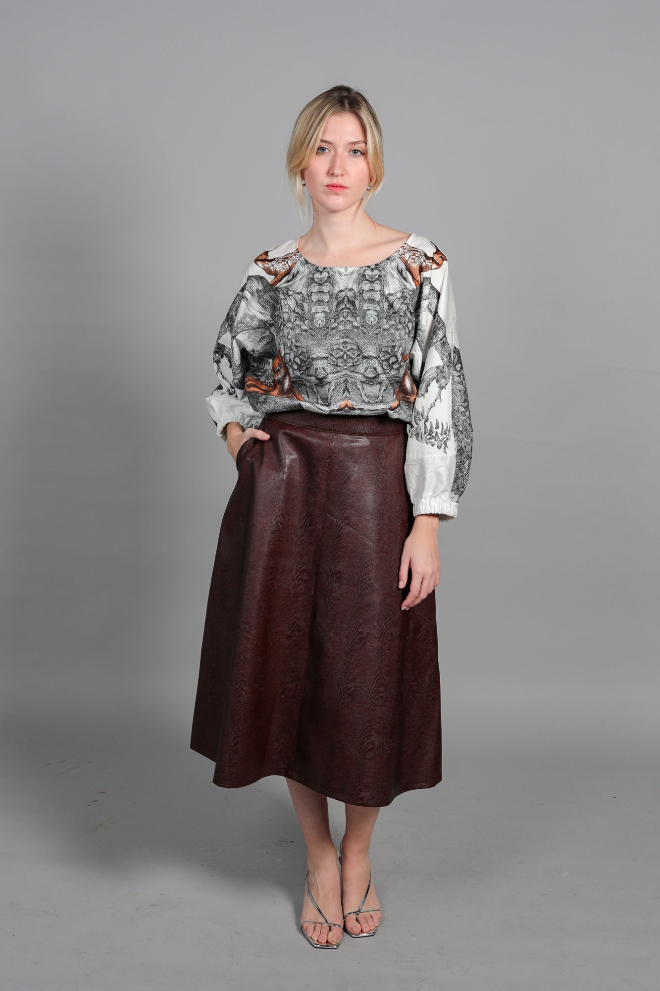 Look de bureau chic avec la Blouse Audrey imprimée. Portée sous un blazer bleu marine avec une jupe en cuir bordeaux. Silhouette sophistiquée et confortable pour la journée de travail. Style parisien effortless.