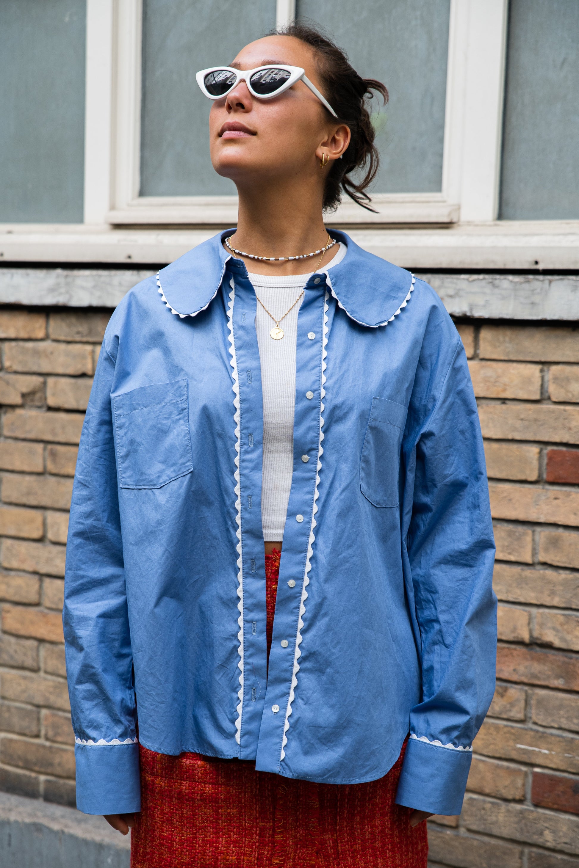 femme portant le chemisier Carlis en popeline de coton italien bleu made in France, col rond avec croquet