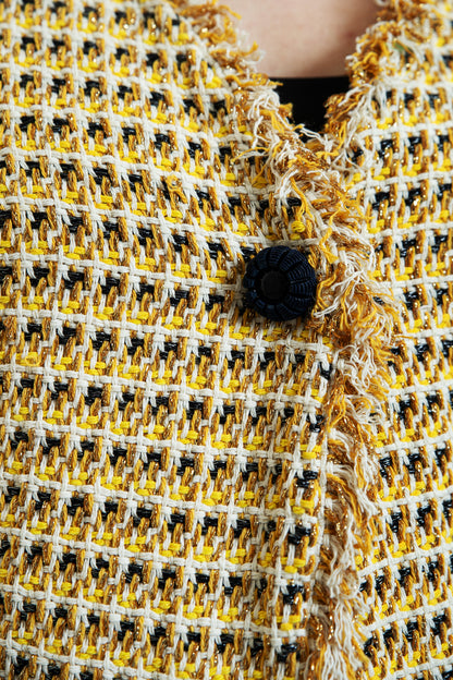 Détail bouton signature noir brodé et tissage tweed de coton luxe jaune doré et crème, fils métallisés, finitions franges cousues main, gilet made in France