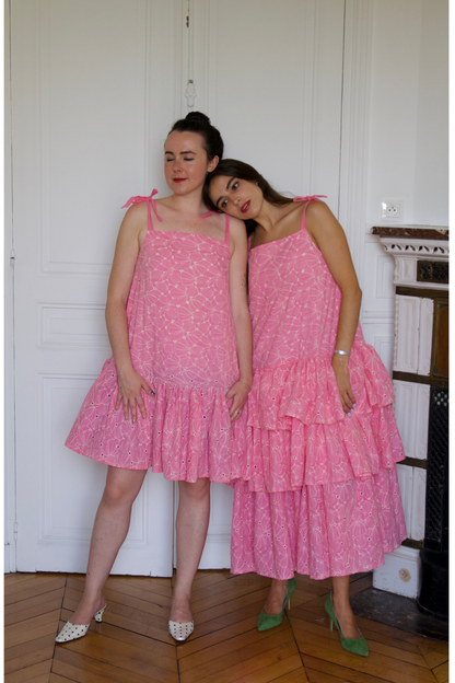 Plan de détails sur le buste : Un autre zoom sur le haut de la robe longue en broderie anglaise rose tendre, mettant en valeur l'artisanat français.