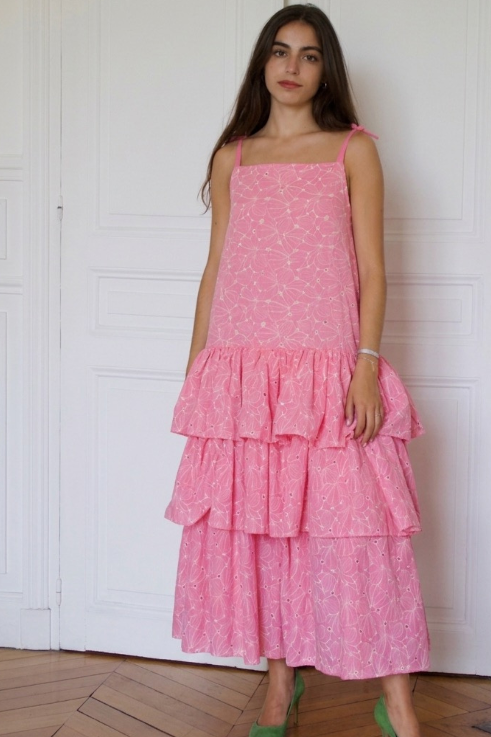 Silhouette de la robe longue rose La Sévillane en broderie anglaise italienne, avec ses trois volants couture et ses fines bretelles à nouer. Tenue invitée de mariage chic.