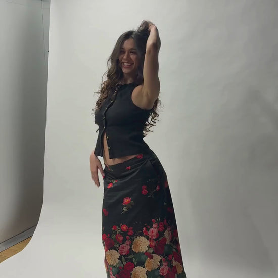Look complet avec la jupe midi Toscane Carlis — associée à un crop top noir ajusté et des escarpins vernis, imprimé roses botaniques sur satin de coton noir. Tenue soirée ou mariage invitée, made in France.