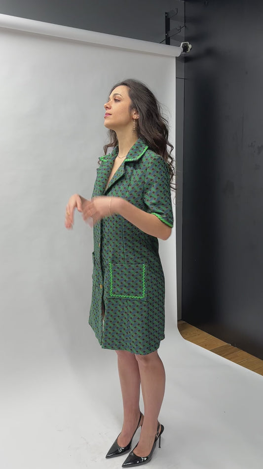 Robe courte trapèze en jacquard de coton italien, imprimé géométrique vert forêt et bleu canard, col chemisier oversize, boutonnage doré sur toute la longueur, finitions passepoil vert et poches plaquées — coupe rétro-chic inspirée des années 70, façonnée en France par Carlis
