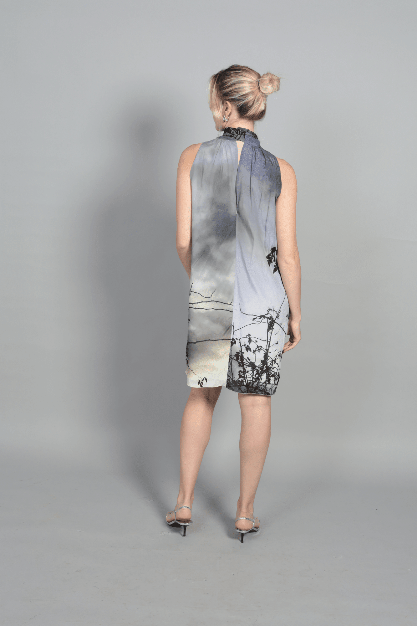 "Gros plan sur le tissu fluide en soie de la robe Bella. L'imprimé paysage onirique offre des nuances subtiles de gris et de blanc. Texture douce et légère, idéale pour les tendances mode 2026 et les matières naturelles de luxe."