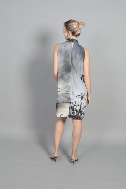 "Gros plan sur le tissu fluide en soie de la robe Bella. L'imprimé paysage onirique offre des nuances subtiles de gris et de blanc. Texture douce et légère, idéale pour les tendances mode 2026 et les matières naturelles de luxe."